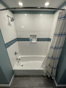 remodeled bathtub/shower with white walls and blue tile