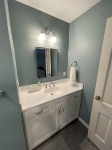 remodeled bathroom with white cabinets and white countertops and blue walls