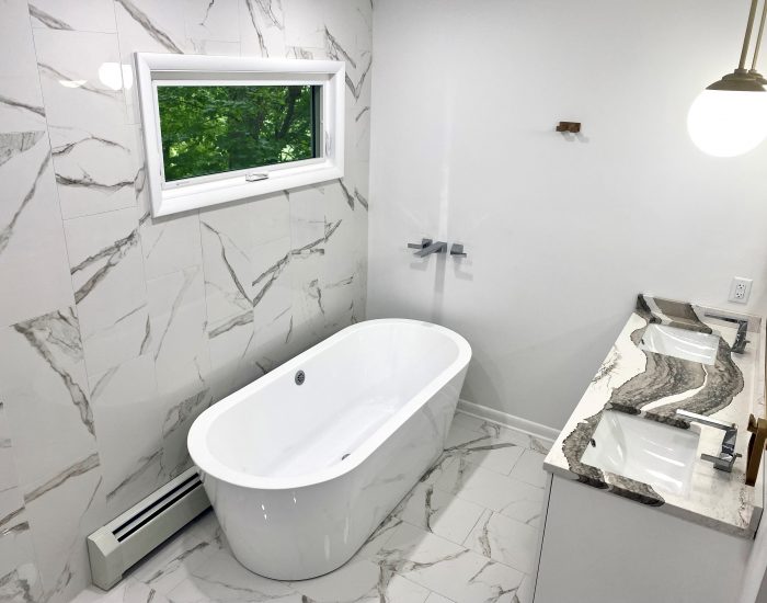marbled bathroom walls and countertops with cool grey and white swirl pattern with close up of porcelain bath tub