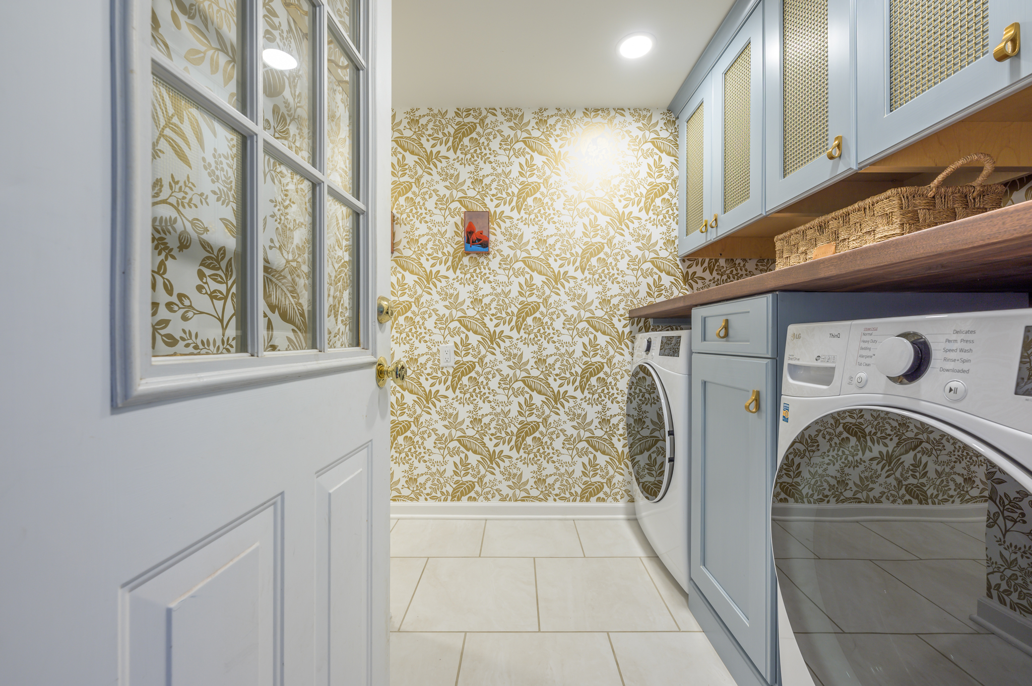 paisley and leaf pattern that is gold and white on walls in laundry room