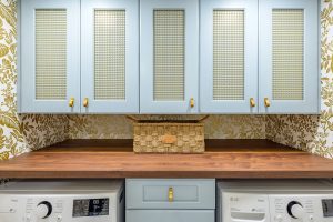 cool blue cabinets with gold handles above laundry machines