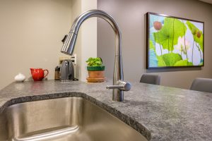 newly remodeled kitchen sink with stainless steel faucet in island of kitchen countertop